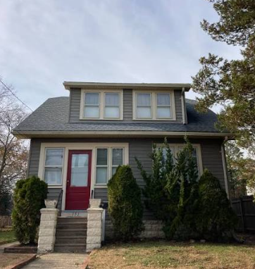 A two-story home with a red front door, bought in as-is condition